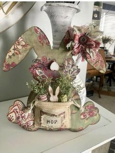 a vase with flowers in it sitting on top of a table next to a bunny