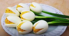 several pieces of hard boiled eggs on a white plate with green onions and spring flowers