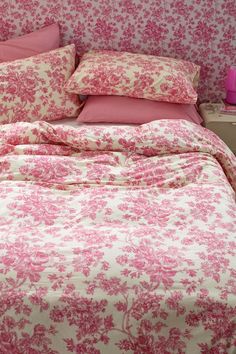 a bed with pink and white floral bedspread, pillows and pillowcases