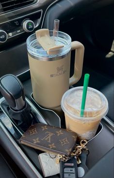 there is a drink and wallet in the cup holder on the car dashboard with other items