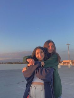 two girls hugging each other in the middle of an empty parking lot