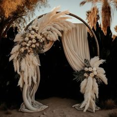 an outdoor wedding arch decorated with flowers and feathers