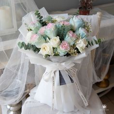 a bouquet of flowers sitting on top of a white cloth covered table next to a candle