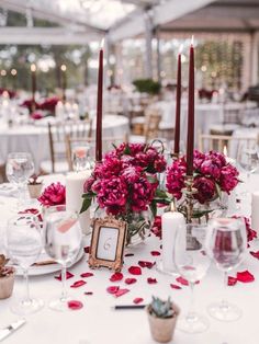the table is set with candles, flowers and wine glasses for an elegant wedding reception