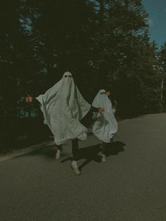 two people dressed as ghost walking down the street