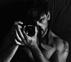 a shirtless man taking a selfie with his camera in front of the mirror