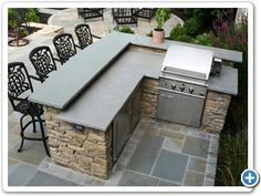 an outdoor kitchen with grill and seating area