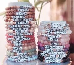 two stacking bracelets with words on them sitting next to a vase filled with flowers