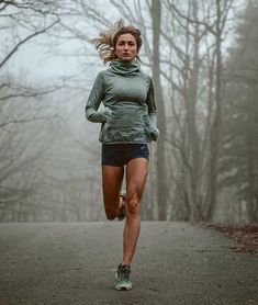 a woman running in the woods on a foggy day