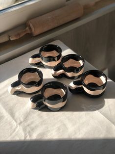 five black and white ceramic bowls sitting on top of a table next to a window