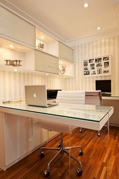 a glass desk with a laptop on top of it in front of a white wall
