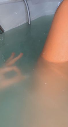 a person in a bathtub with their hand out to touch the side of the tub