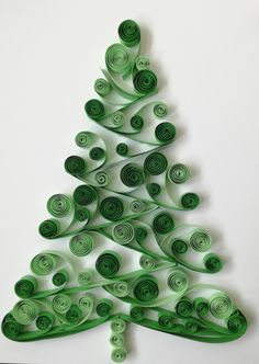 a green christmas tree made out of rolled up spirals on a white surface with the shape of an ornament in the center