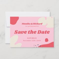 save the date card with pink and red paint splattered on it, sitting on a marble surface