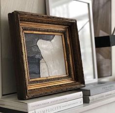 there is a framed painting on top of some books