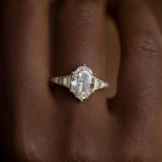 a woman's hand with an engagement ring on top of her finger, showing the center stone