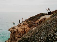 people standing on the edge of a cliff overlooking the ocean