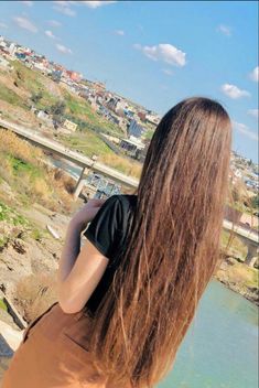 a woman with long brown hair is looking at the water