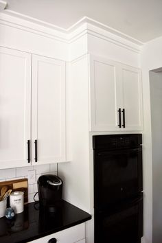 a black stove top oven sitting inside of a kitchen next to white cupboards and drawers