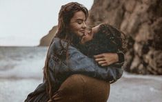 a man and woman hug each other on the beach
