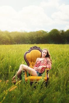 a woman sitting in a yellow chair in the middle of a field with tall grass