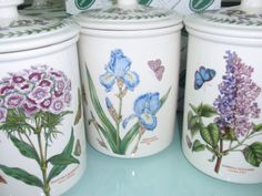 three ceramic canisters with flowers painted on them
