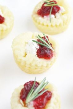 small appetizers with cranberry sauce and cheese on them are arranged on a white surface