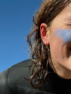 a close up of a person with blue paint on their face and nose, looking at the camera