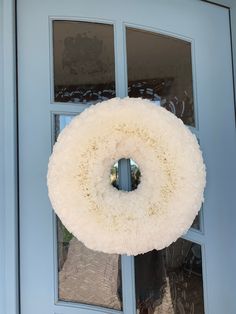 a wreath hanging on the front door of a house with frosted glass and blue doors