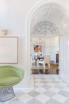 a green chair sitting in the middle of a living room next to a white table