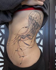 a woman's stomach with a jellyfish tattoo on it