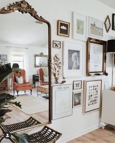 a living room filled with furniture and pictures on the wall next to a plant in a vase