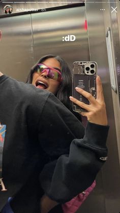 a woman taking a selfie in an elevator with her cell phone up to her face