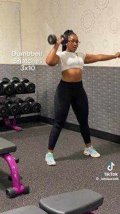 a woman is doing dumbbell squats in the gym