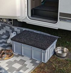 there is a dog bowl and some shoes on the ground next to an rv with it's door open