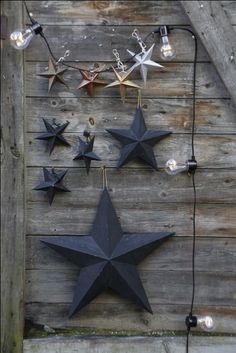 several stars are hanging on the side of a wooden building with string lights attached to them