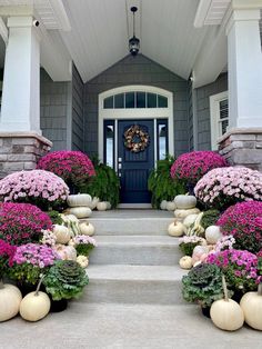 the front entrance of a house with flowers and pumpkins on the steps to it