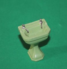 two tiny birds perched on top of a green pedestal sink with water running down the side