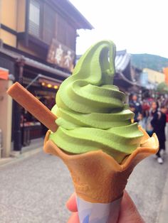 a hand holding up a green ice cream cone