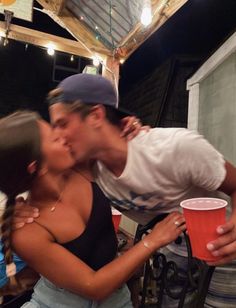a man kissing a woman on the cheek with a red cup in front of him