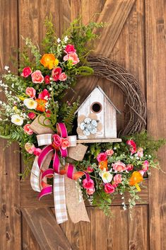 a wreath with flowers and a birdhouse on it
