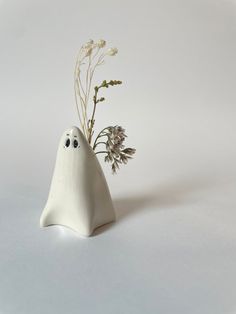 a small white ghost vase with flowers in it