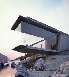 an unusual house on the edge of a mountain with water and rocks in front of it