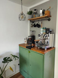a green cabinet sitting in the corner of a room next to a potted plant