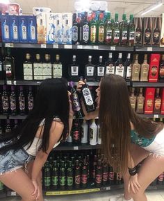 two women are looking at bottles in a liquor store