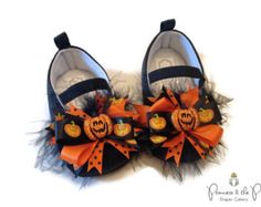 a pair of baby shoes with pumpkins and feathers on the front, one has a jack - o'- lantern design