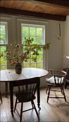 two chairs and a table in front of a window with plants on the windowsill