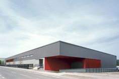 an industrial building with red and grey panels on the side of it's roof