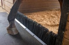 a horse's legs sticking out of the side of a stall with hay in it