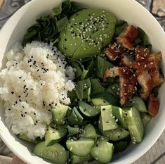 a white bowl filled with rice, cucumbers and other vegetables next to meat